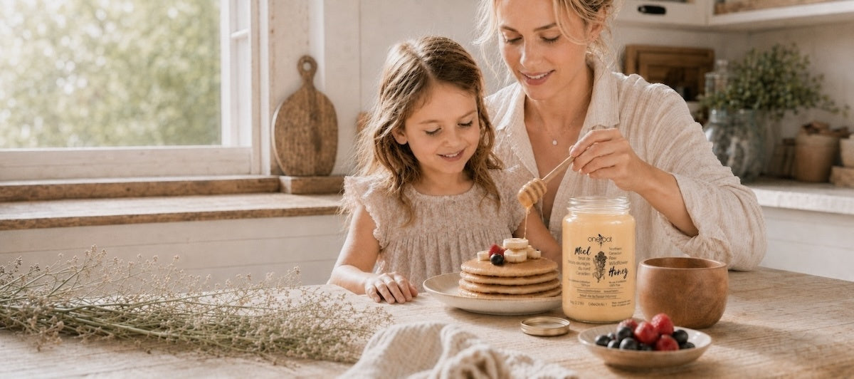 Mom and daughter in kitchen sharing pancake with honey