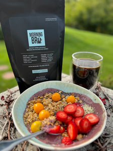 Breakfast scene with a bowl of fruit and granola, a cup of coffee, and a package labeled 'Morning Brew' on a natural background.